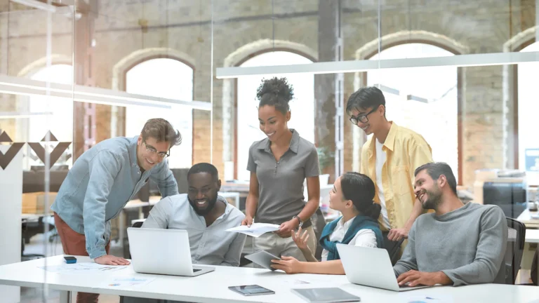 Group of business people communicating with each other and discussing project results while sitting together behind the glass wall in the creative office.