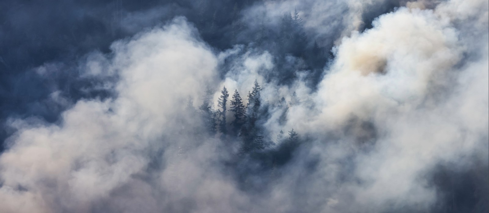 BC Forest Fire and Smoke over the mountain near Hope during a hot sunny summer day. British Columbia, Canada. Wildfire natural disaster